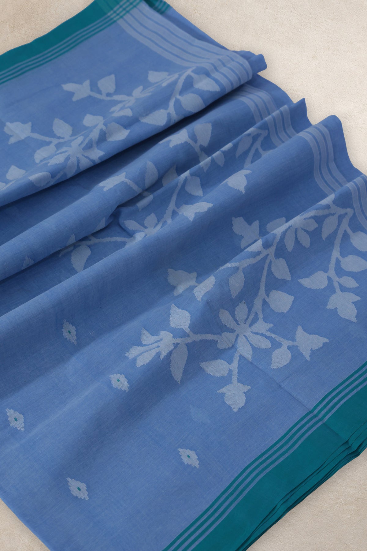 Close up of handwoven Jamdani flower motifs on greyish blue cotton