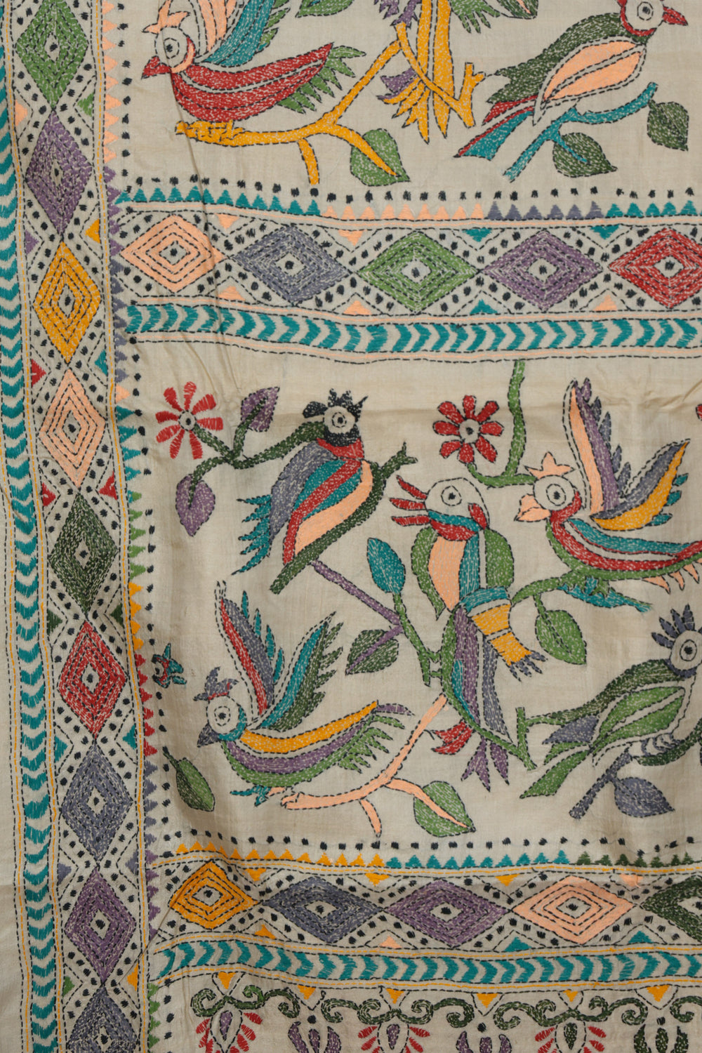 Close up of hand stitched Kantha parrot and leaf motifs on beige Gachi Tussar