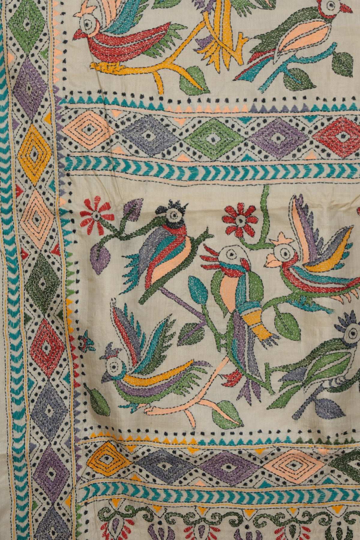 Close up of hand stitched Kantha parrot and leaf motifs on beige Gachi Tussar
