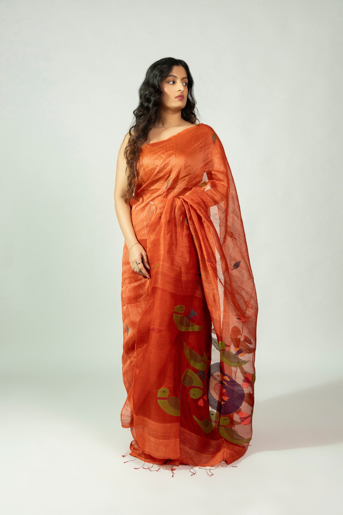 Komola Tia rust orange silk linen saree with leaf motifs and green parrot pallu